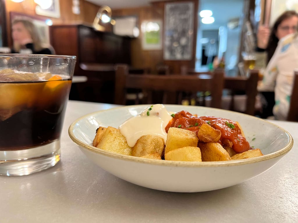 Tapasy w Barcelonie w zabytkowym barze na stoliku patatas bravas i wermut